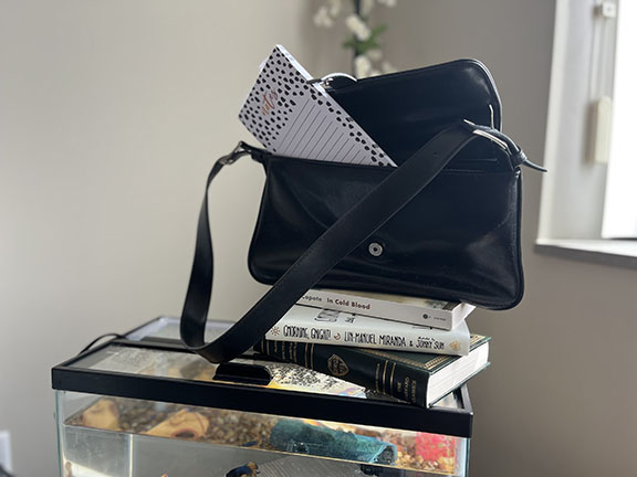 black purse sitting on top of books on a fish tank with a notepad sticking out of it
